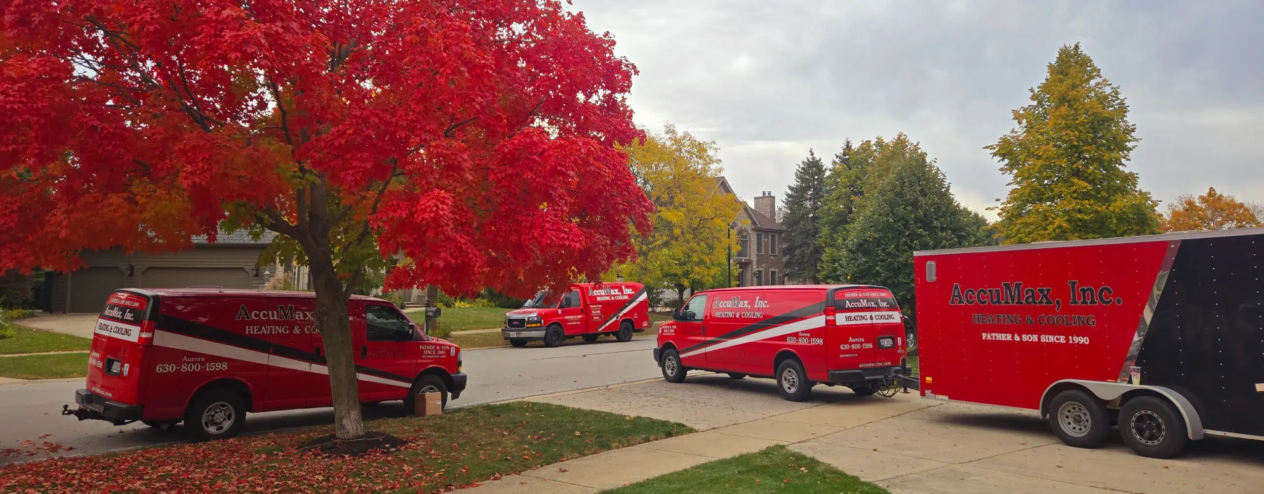 AccuMax service trucks and equipment trailer parked outside a home in the Aurora, Illinois area