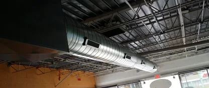 Spiral sheet-metal ductwork installed across the ceiling of a commercial space