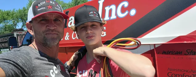 AccuMax father and son HVAC technicians smiling in front of a service van